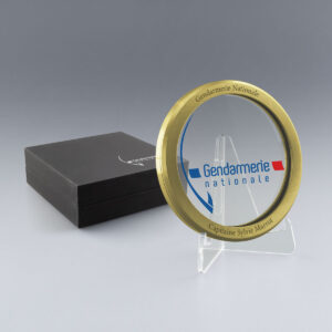 Médaille en verre et métal doré personnalisable Gendarmerie Nationale, avec boîte cadeau fermée et chevalet transparent.