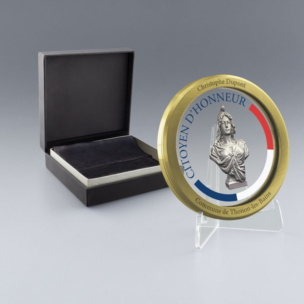 Médaille du Citoyen d’Honneur dorée en verre et métal, personnalisable, livrée dans un coffret ouvert avec intérieur en suédine noire.