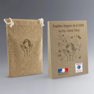 Trophée en bois trapèze avec marquage éco-responsable et sac en liège, remis lors d’un événement environnemental.